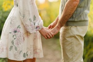 Couple in light colored outfits sharing intimate moments in a sunlit outdoor setting.