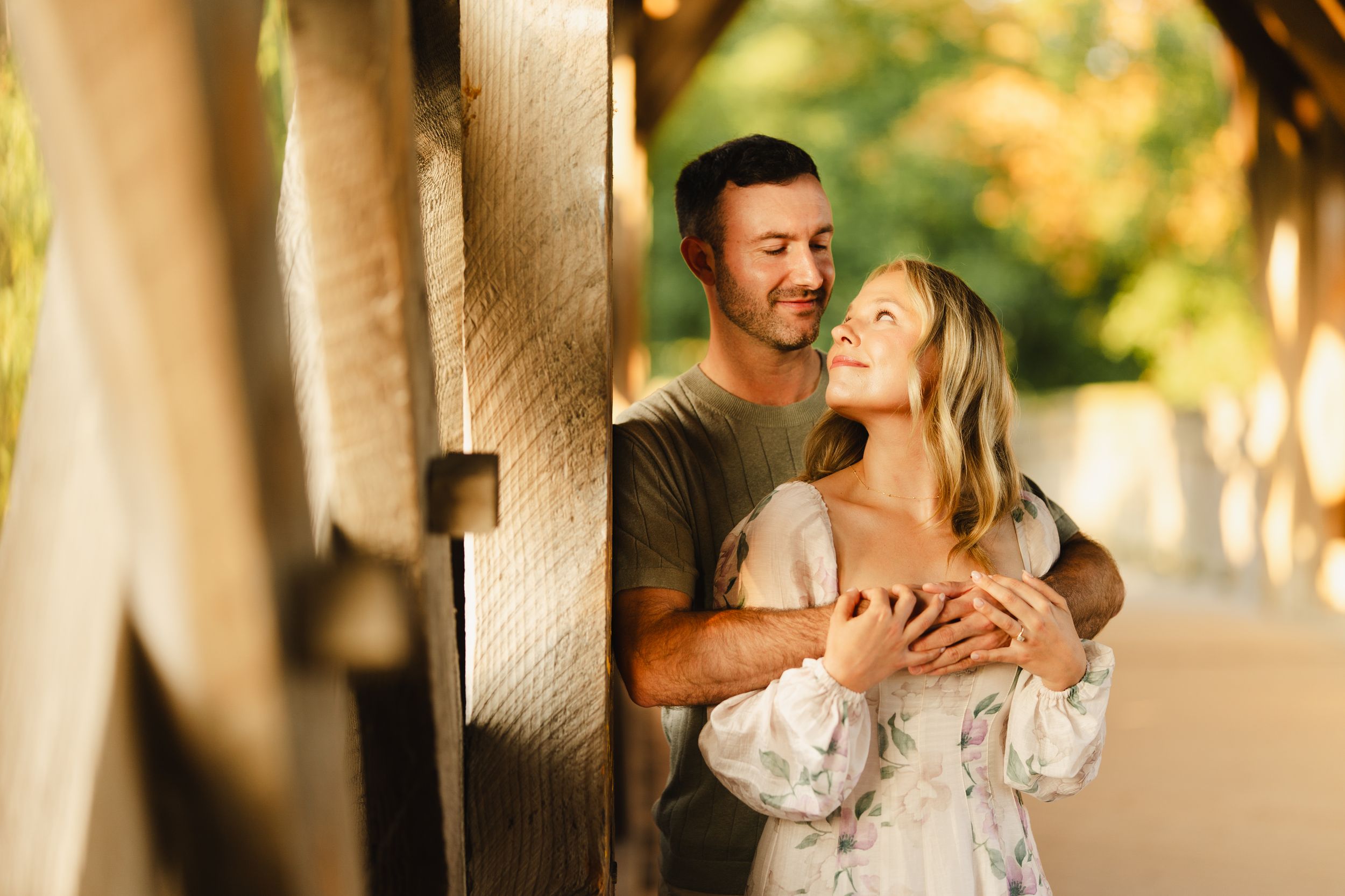 Sweet moments captured between a couple on a covered wooden walkway.