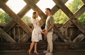 Romantic photoshoot under a wooden lattice structure in warm evening light.