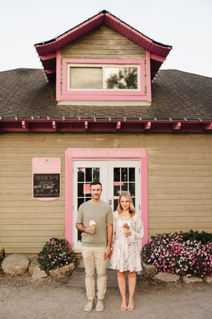 Pink-trimmed ice cream shop exterior with tan walls and flowering bushes.
