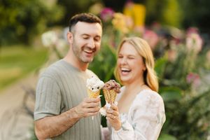 Happy couple enjoying ice cream cones together in a garden.