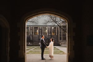 Silhouetted couple stands in gothic archway during romantic photoshoot.