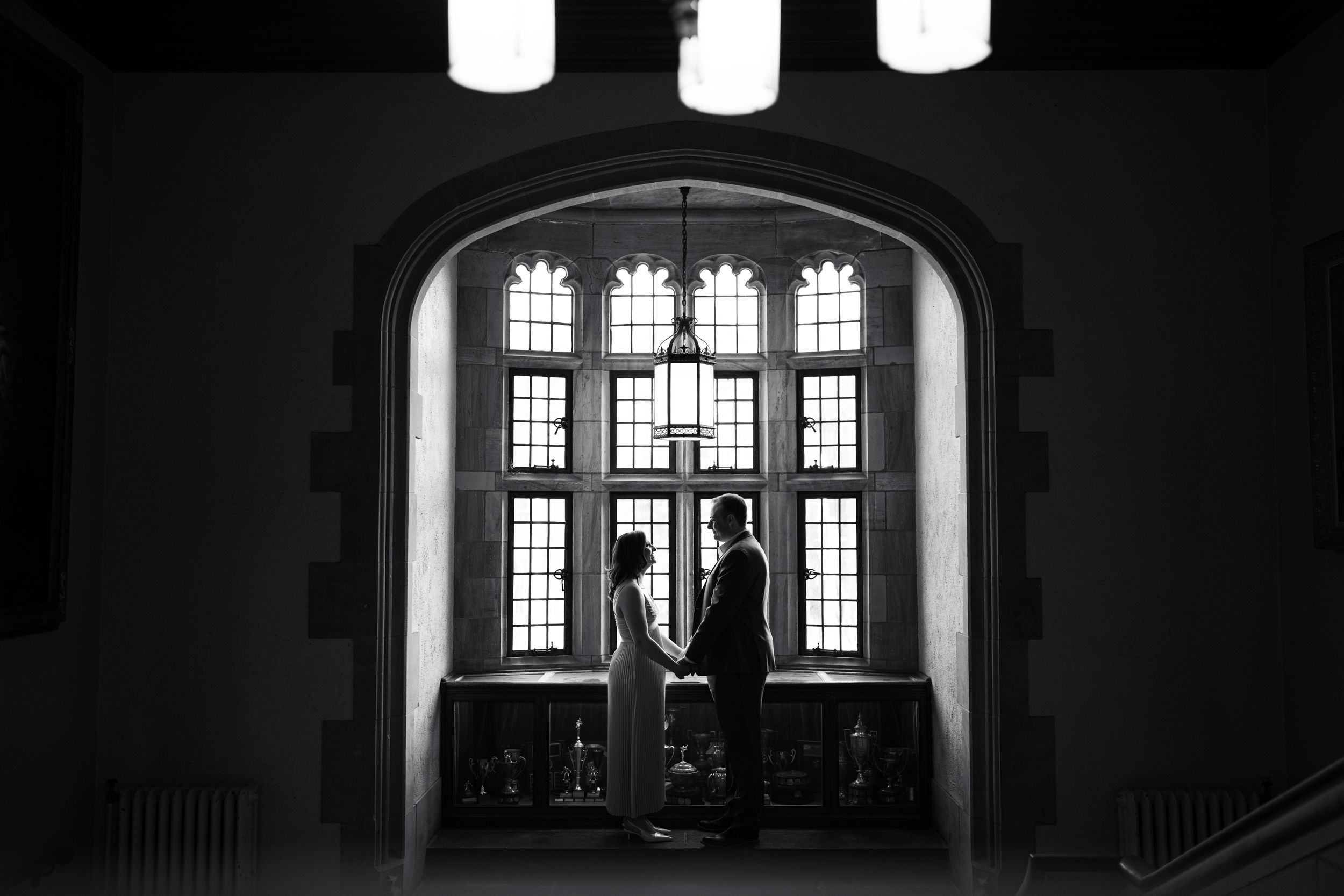 Dramatic silhouette against arched windows in dark interior.