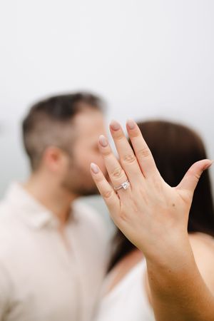 Close-up of a sparkling engagement ring on a hand with neutral manicured nails.