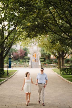 Couple walking together on tree-lined pathway during summer.
