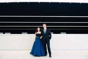 A couple in formal attire dancing in an elegant white and black space.