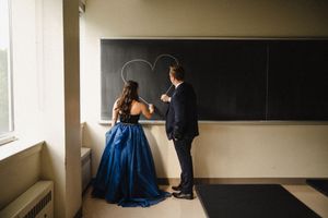 An elegant indoor photoshoot featuring dramatic lighting and formal attire.