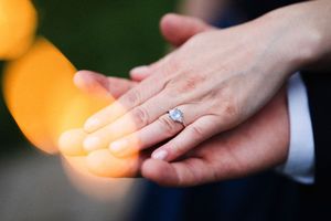 Close-up of hands holding glowing sparklers with engagement ring visible.
