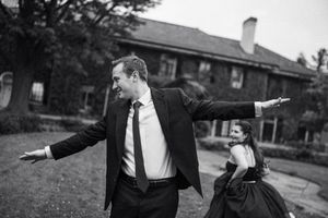 Artistic black and white shot of couple with arms outstretched in joyful dance.