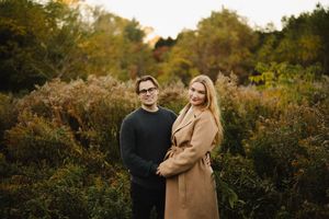 A couple strolling through an autumn landscape at sunset.