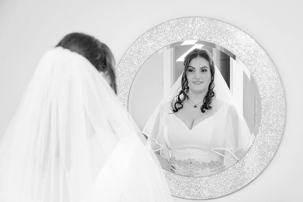 a beautiful bride looking at herself in the mirror