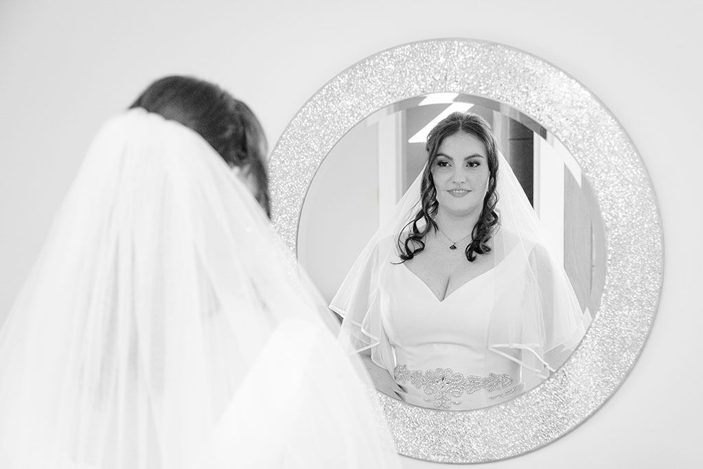 a beautiful bride looking at herself in the mirror