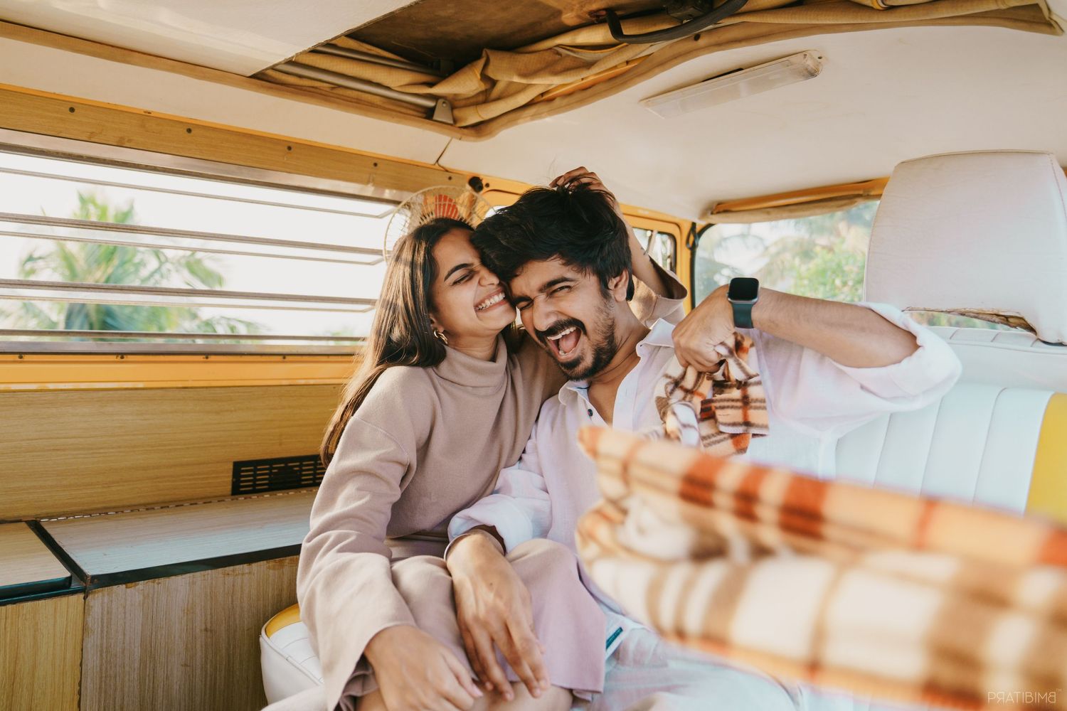 Happy couple taking a selfie together inside a vintage yellow van during a road trip adventure.