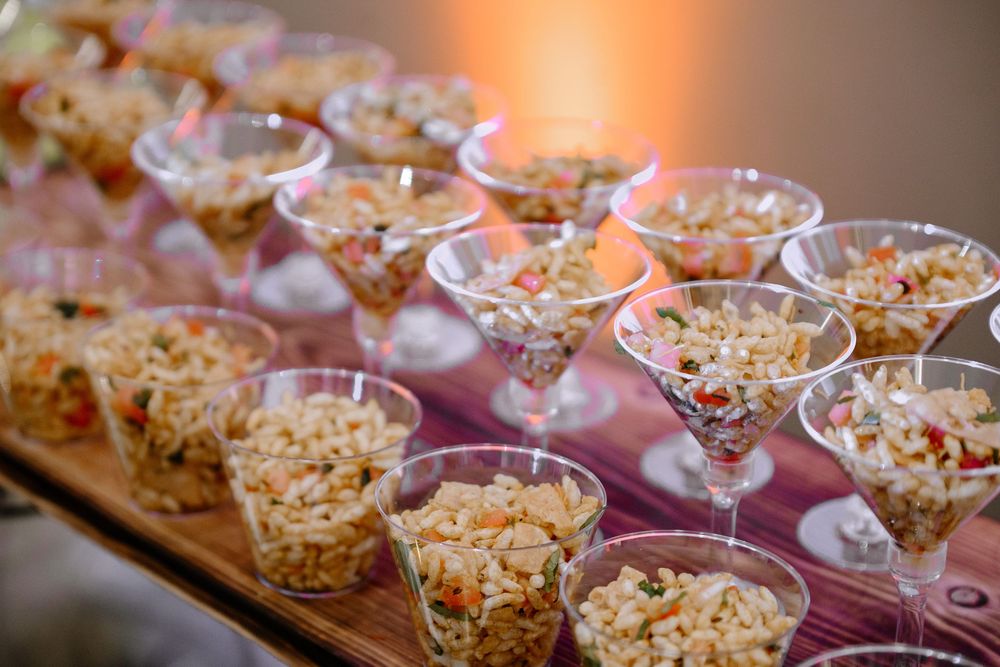 Elegant martini glasses and bowls filled with colorful pasta salad displayed on a buffet table at a catered event.
