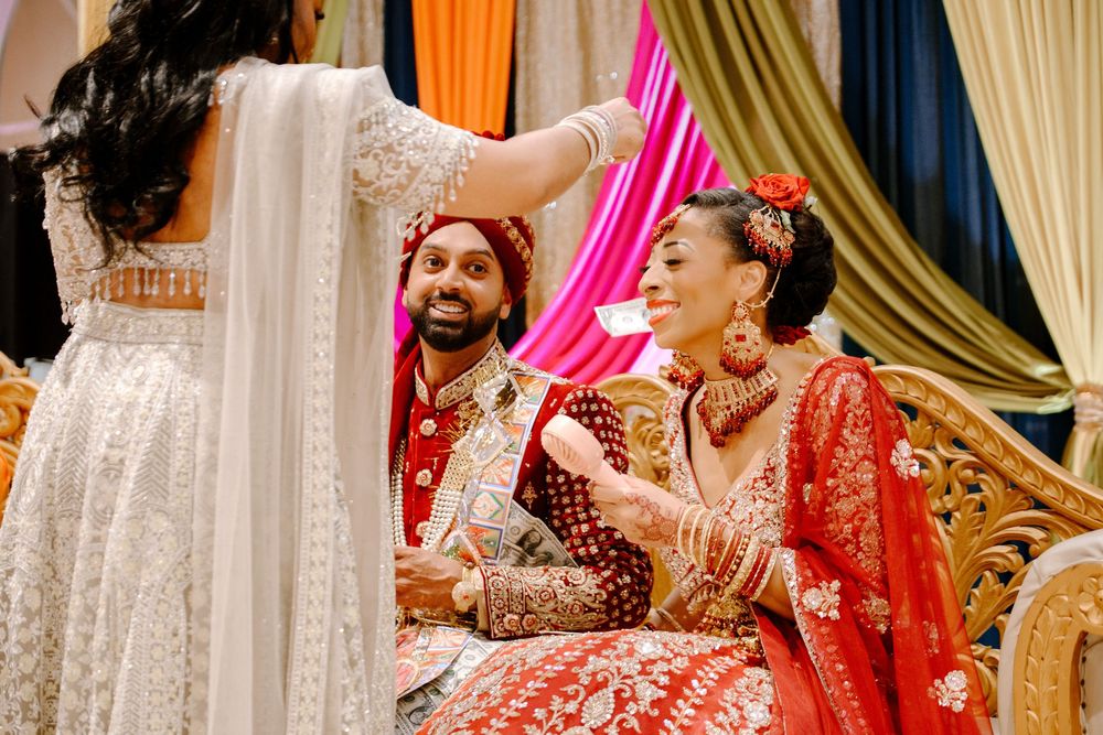 Indian bride and groom in traditional red and gold wedding attire during a vibrant Hindu wedding ceremony.