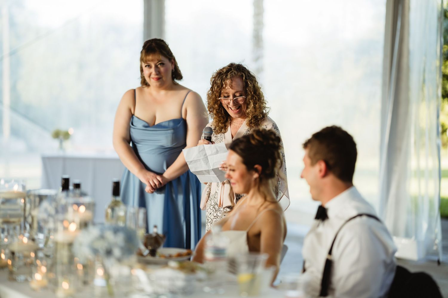 Bride receiving a gift from bridesmaids in blue dresses at an elegant wedding reception.