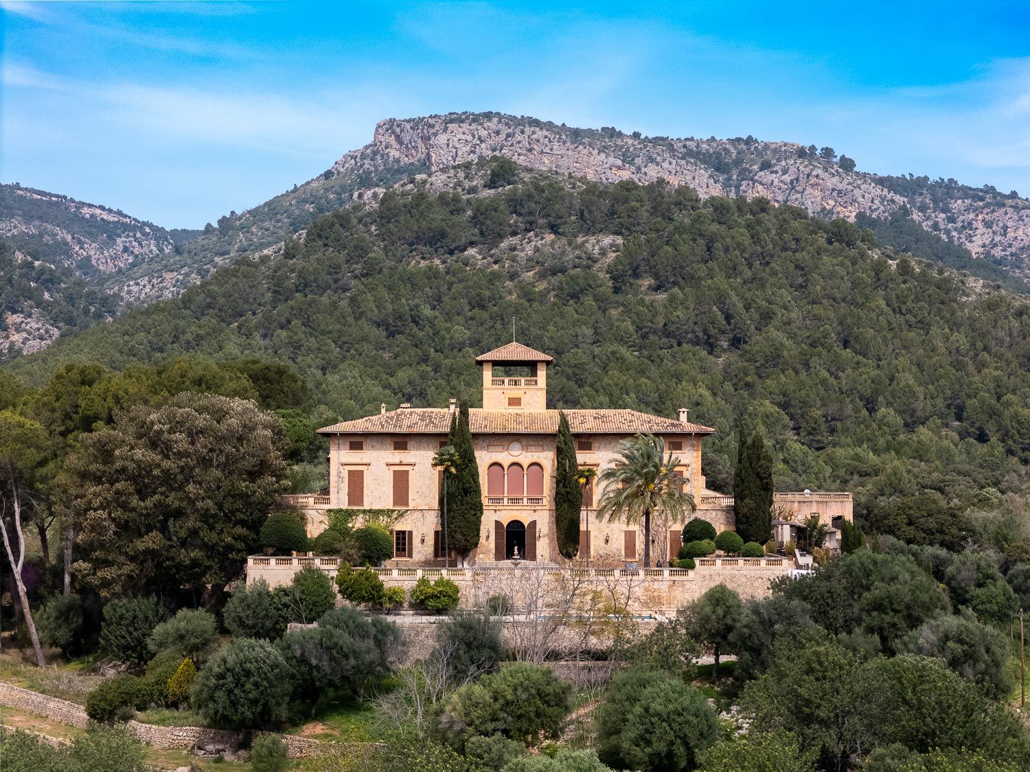 a typical mallorcan finca surrounded by the forest with a wedding ceremony set up in front of it