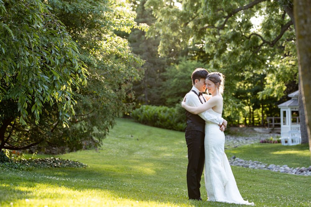 Bride and groom embracing in lush green garden, sharing romantic moment during sunset at the civic garden complex in london, ontario.