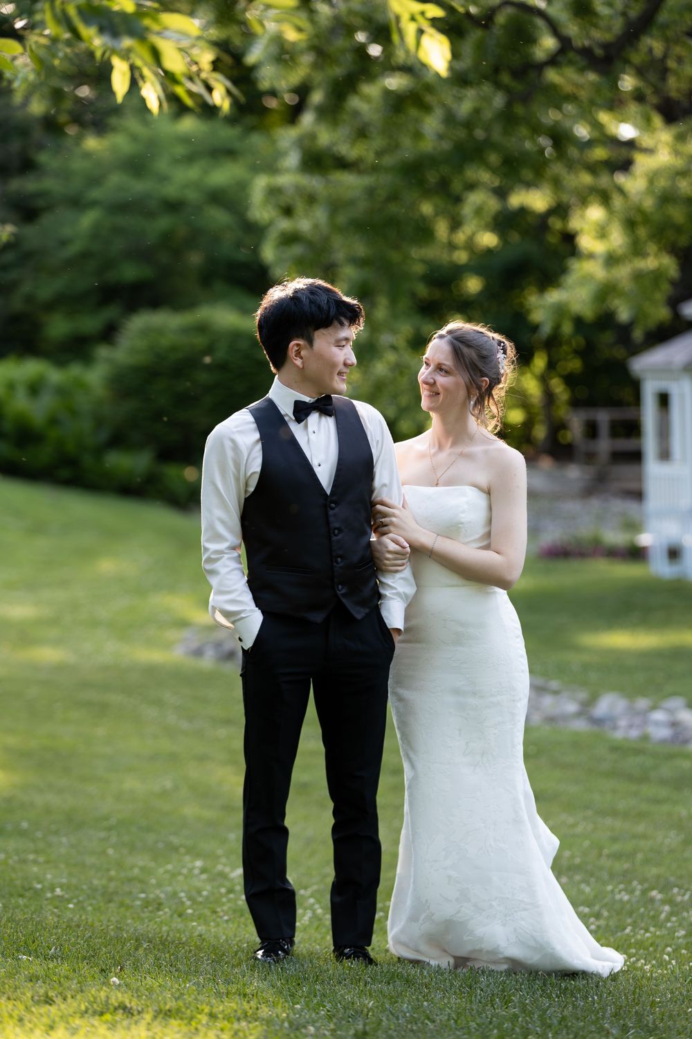 A bride and groom share a loving glance while standing on green grass during sunset at the civic garden complex in london, ontario.