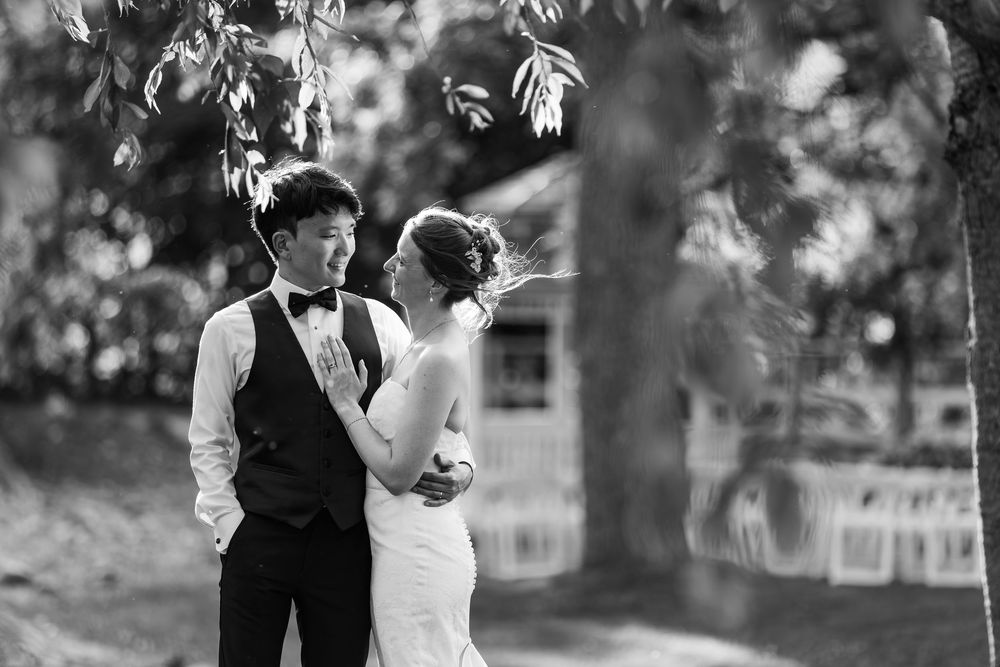 Black & white photo of a bride & groom embracing under trees at their wedding reception at the civic garden complex in london, ontario.