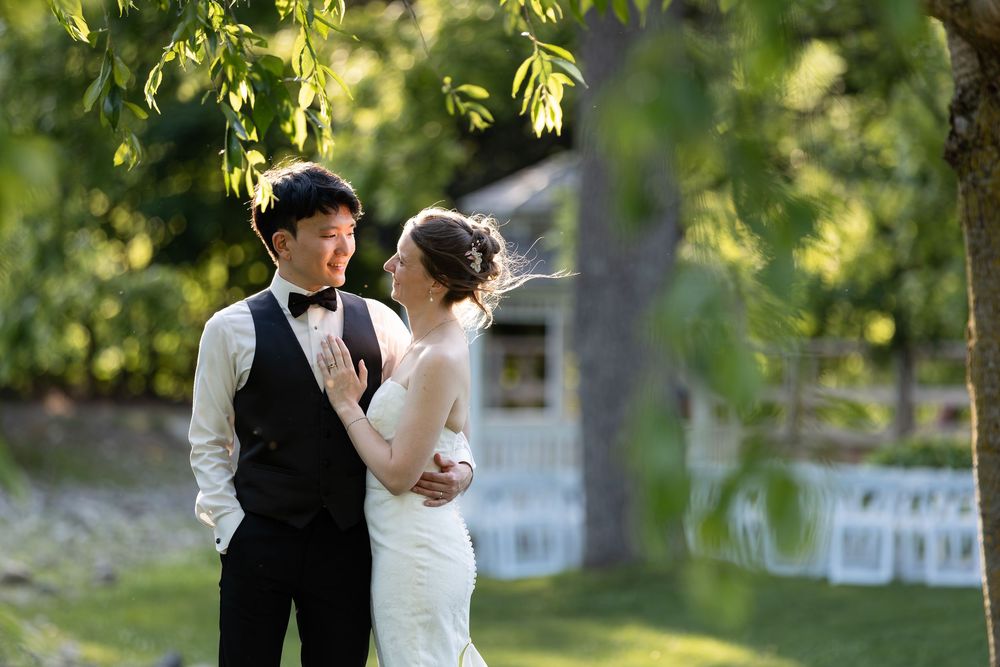 Bride and groom share a romantic moment outdoors under lush green trees at the civic garden complex in london, ontario.