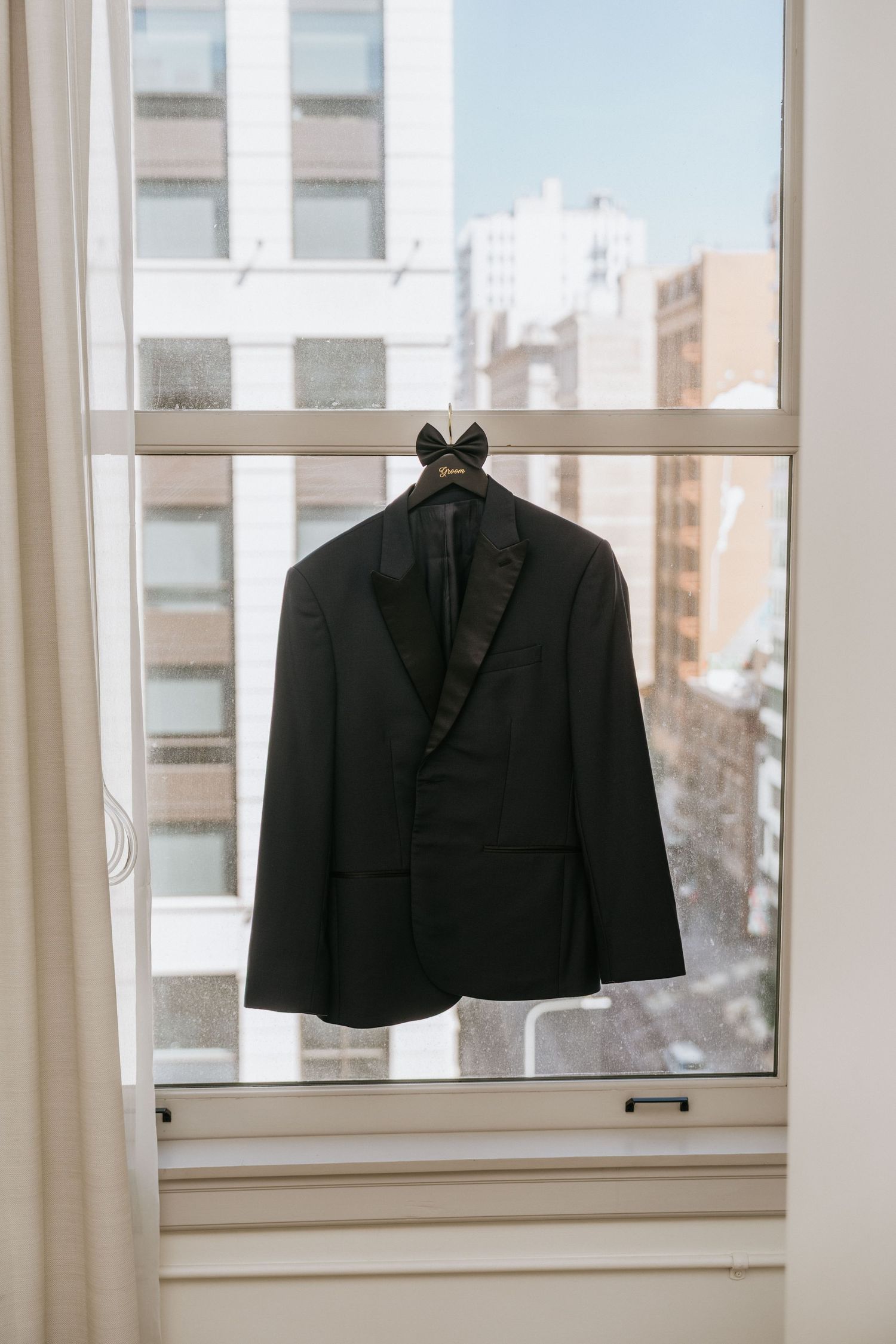 Black tuxedo jacket hanging in a window before the wedding at Sonder The Craftsman in Los Angeles.