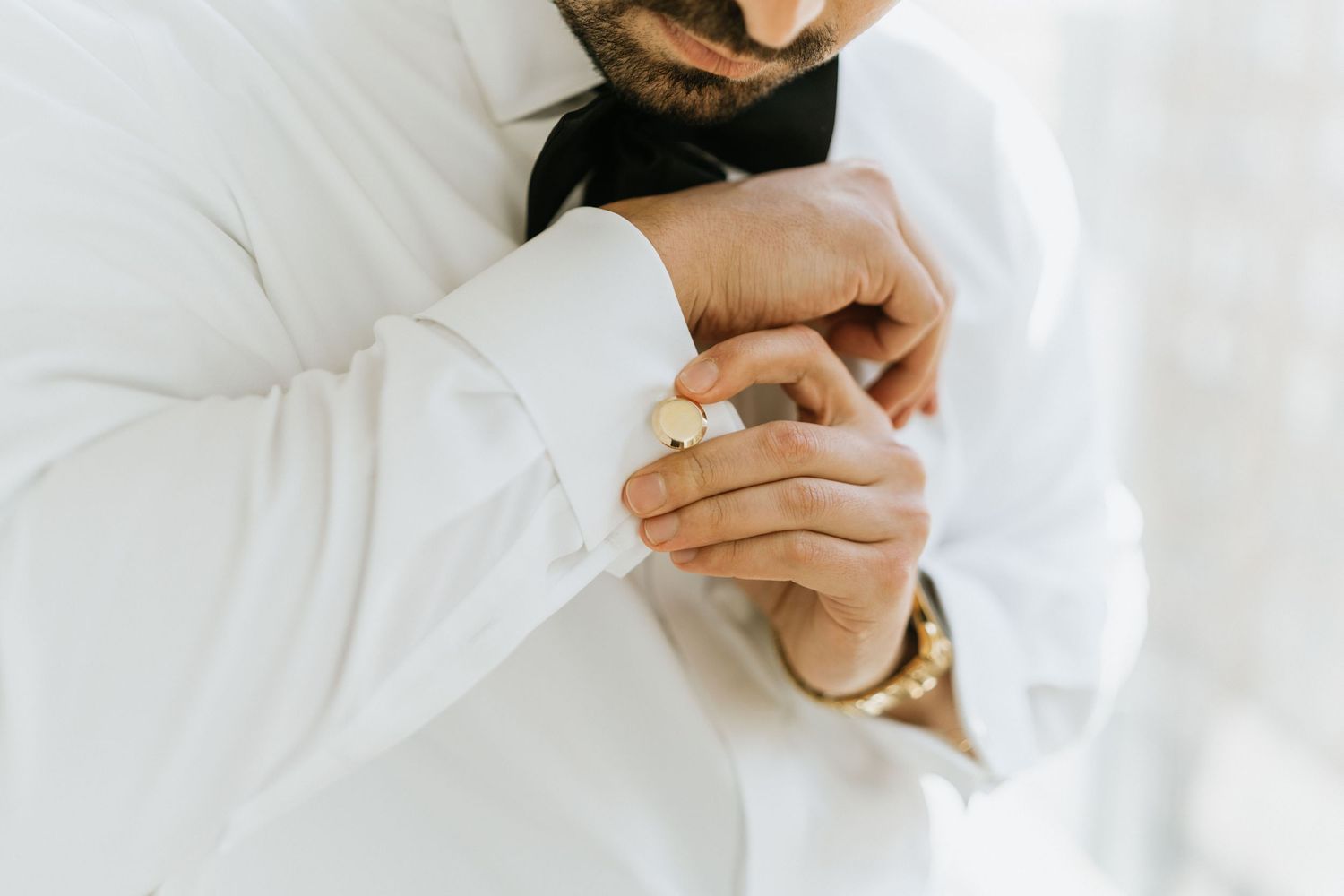 Close-up of the groom fastening his cufflink while getting ready.