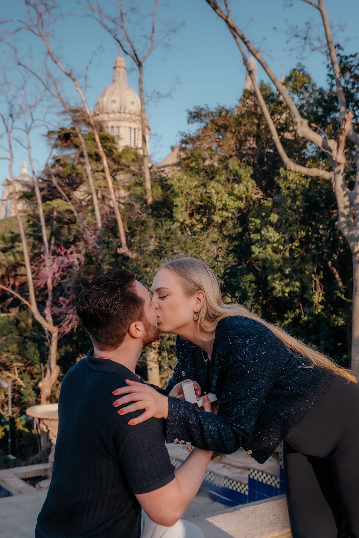 Bubbly couple celebrating their secret engagement surrounded by lush greenery on a hidden Montjuic path.