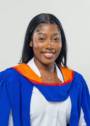 Smiling young woman in blue and orange graduation gown poses for a professional graduation portrait photo.