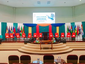 Decorated stage with welcome banner and international flags at graduation ceremony.