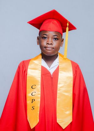 Student in red graduation cap and gown with gold CCPS stole poses for school portrait.
