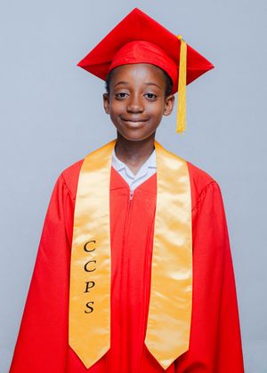 Young student in red graduation cap and gown with gold CCPS honor stole smiling for official portrait.