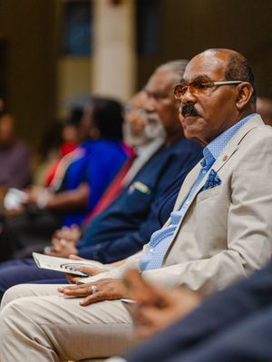 Distinguished man in beige suit attends formal academic graduation ceremony.