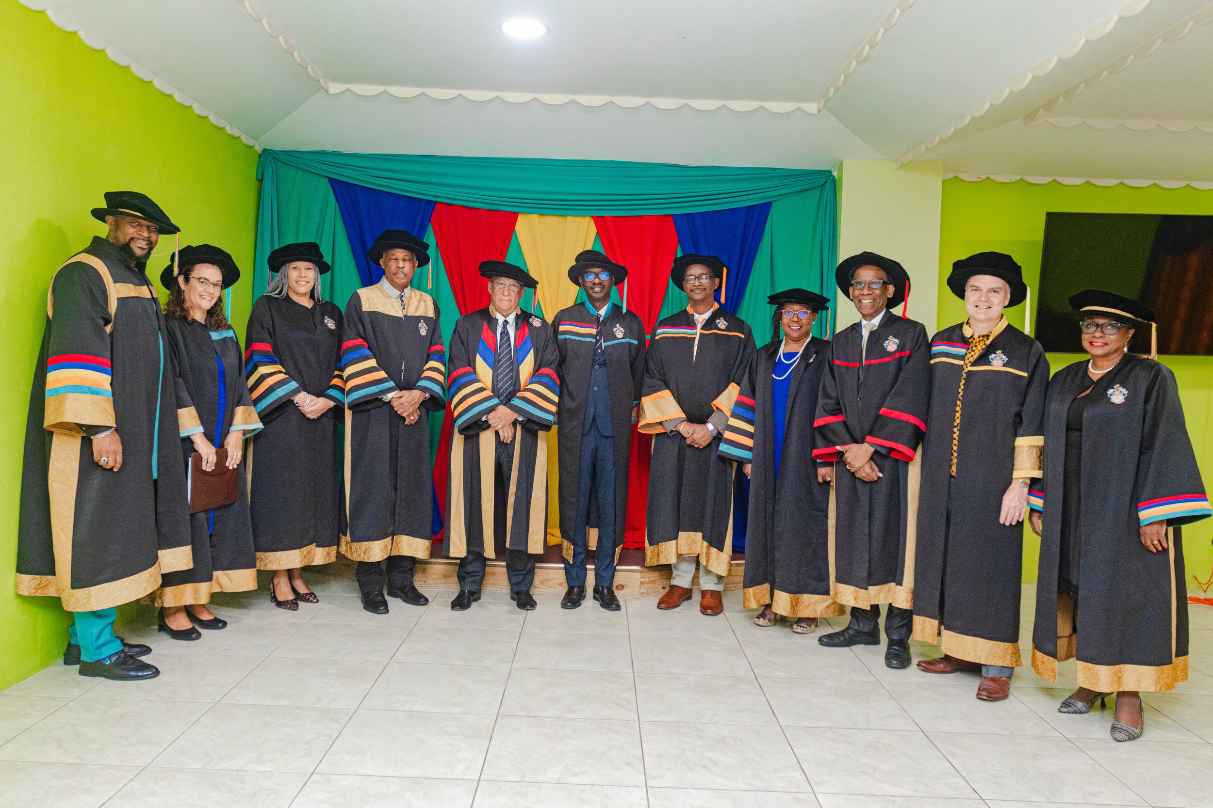 Group of graduates and faculty posing in academic regalia at a graduation ceremony.