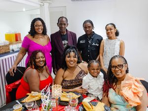 Group of eight people posing together at a festive dinner party celebration.
