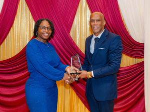 Woman in blue dress receiving a crystal award from a man at a formal ceremony.