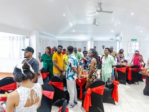Guests mingling at an elegant event venue with black chairs adorned with red bows and ribbon decorations.