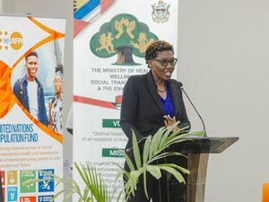 Woman speaking at podium beside UN Population Fund banner at health ministry event.