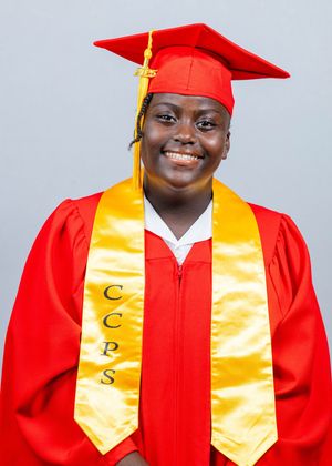 Smiling graduate in red cap and gown with gold CCPS stole poses for official graduation portrait.