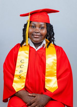 Young graduate in red cap and gown with gold CCPS honor stole smiling for official graduation portrait.