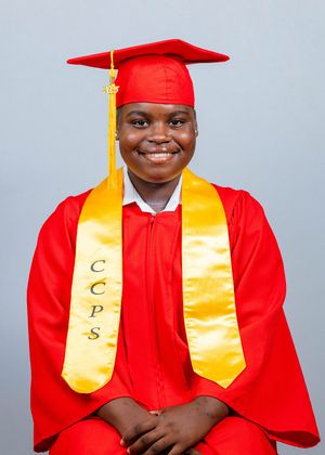 Smiling graduate in red cap and gown with gold CCPS honor stole poses for official graduation portrait.