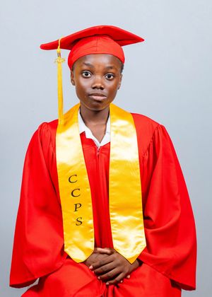 Graduate in red cap and gown with gold CCPS stole poses for formal portrait photo.