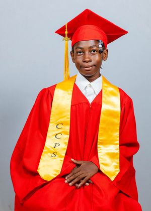 Student wearing red graduation cap and gown with gold CCPS honor stole posing for grad photo.