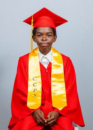 Young student in red graduation cap and gown with gold CCPS stole posed for formal portrait.