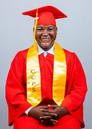 Smiling graduate in red cap and gown with gold CCPS stole poses for official graduation portrait.