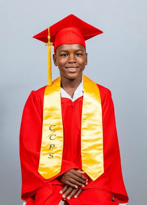 Smiling graduate in red cap and gown with gold CCPS stole poses for graduation portrait.