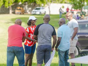 Group of people having a conversation outdoors in a park during a sunny community gathering event.