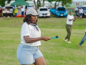 Woman playing with a yo-yo toy at an outdoor community festival event on a sunny day.