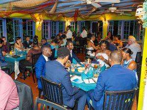 Guests dining at a vibrant Caribbean restaurant during a formal evening event with colorful decor.