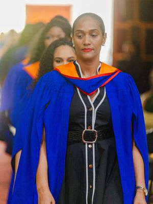 Close-up of a graduate in blue and orange academic regalia at a university graduation ceremony.